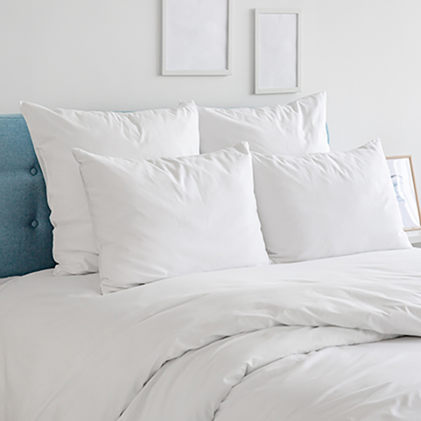 White pillows, duvet and duvet case on a blue bed. White bed linen on a blue sofa. Bedroom with bed and bedding and poster frame mock up on the wall.. Left side view.